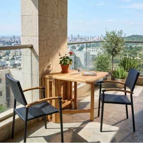 Foldbart teakbord med to sorte stabelstole i UV-beskyttet polyrattan